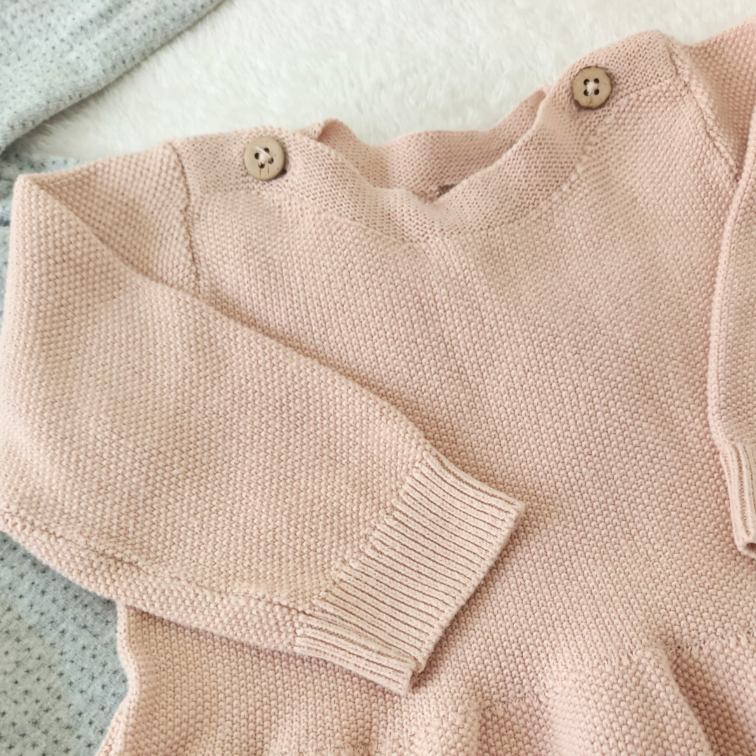 Vestido de punto color rosa empolvado para bebé de la marca Levv, con botones de madera en el hombro y tejido de punto grueso.