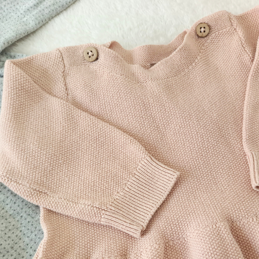 Vestido de punto color rosa empolvado para bebé de la marca Levv, con botones de madera en el hombro y tejido de punto grueso.